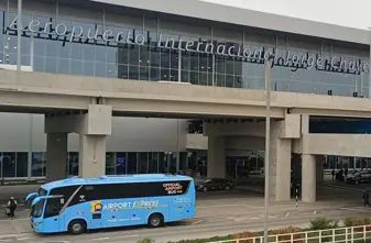 Exterior of the new Jorge Chávez Lima Airport terminal, featuring an Airport Express bus and a taxi at the pickup zone.